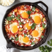 Best ever healthy shakshuka recipe in cast iron skillet with lots of fresh vegetables and crumbled feta.