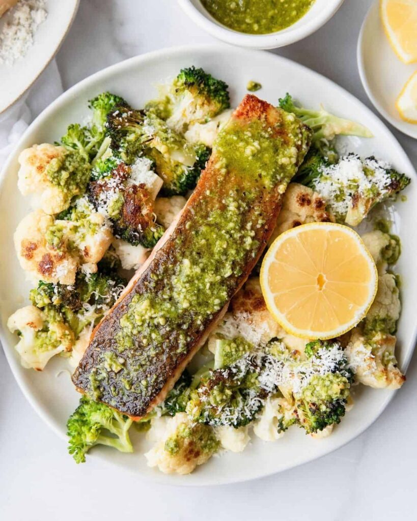 Crispy Pesto Salmon with oven roast parmesan cauliflower and broccoli. The perfect dinner, lunch, or healthy meal prep recipe by Healthful Blondie.