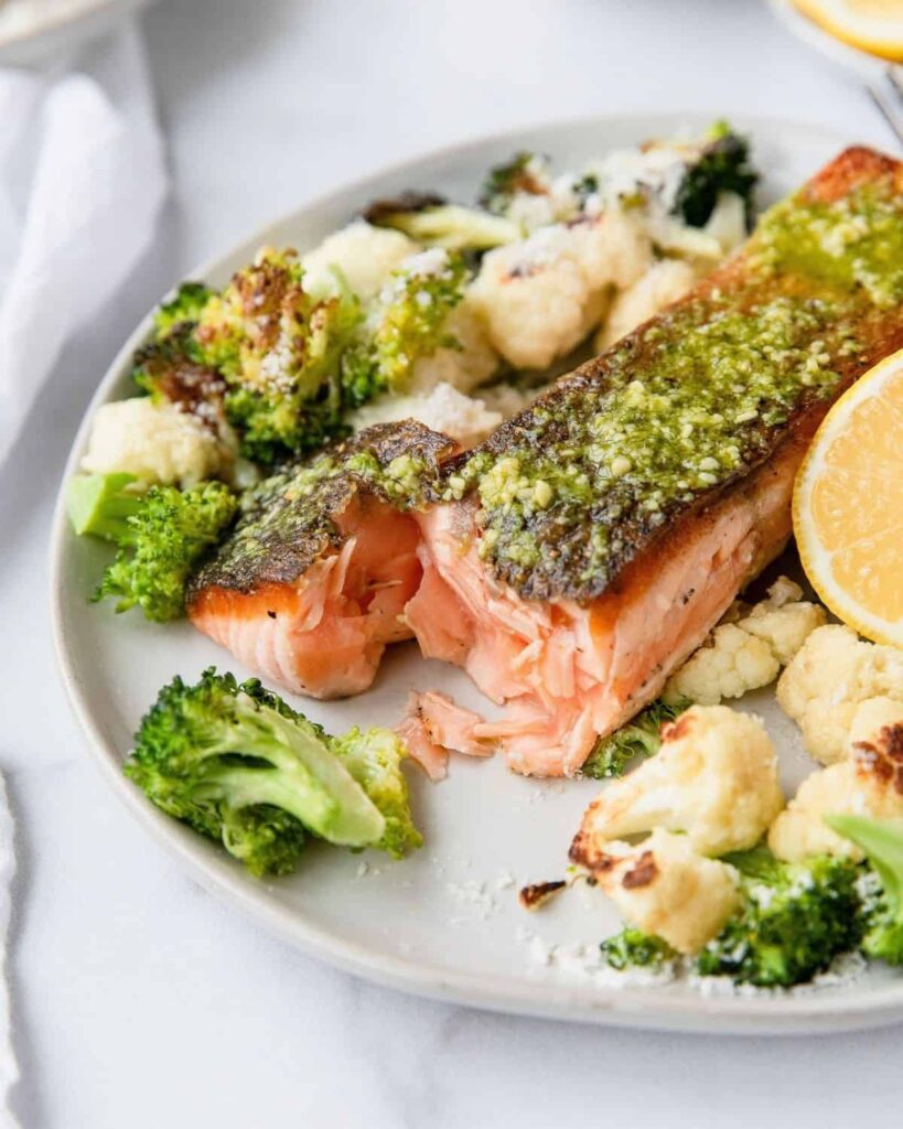 The ultimate flakey salmon with perfect crispy skin. This healthy dinner recipe is by Healthful Blondie x Tati Chermayeff. Topped with healthy pesto and lots of parmesan cheese for a gluten free dinner.