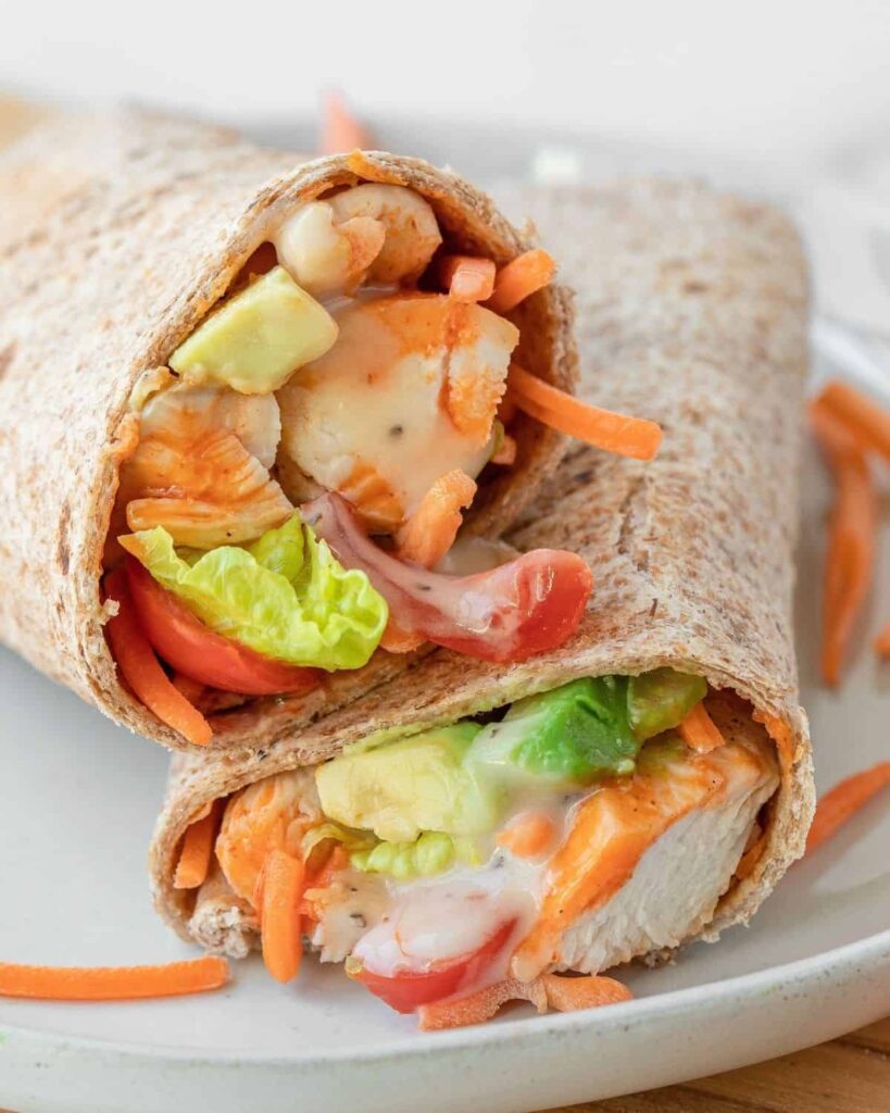 Creamy buffalo chicken caesar wrap. Easy to make, takes 15 minutes, great for meal prep, and super yummy. This healthy lunch recipe calls for low calorie Caesar salad dressing, lots of fresh veggies, creamy avocado, and chicken. 