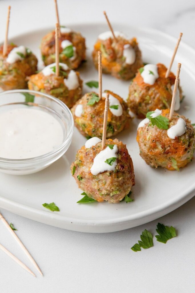 Healthy broccoli cheddar turkey meatball poppers with ranch dressing drizzled on top