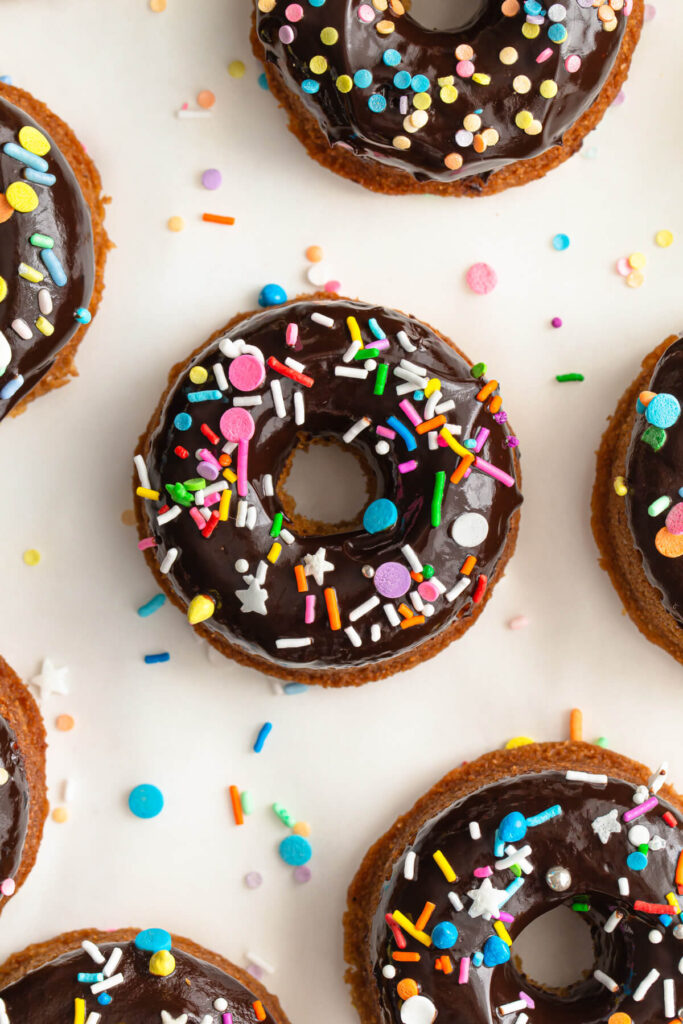 Close up of a healthy baked vanilla donut with thick chocolate frosting and sprinkles.