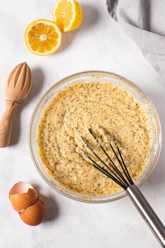 whisking in almond flour and poppy seeds into cake batter