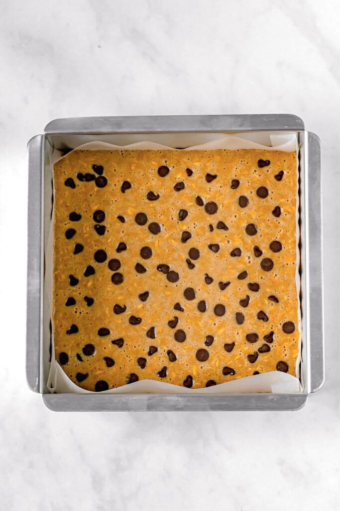 oatmeal bar batter in a line tin with chocolate chips on top