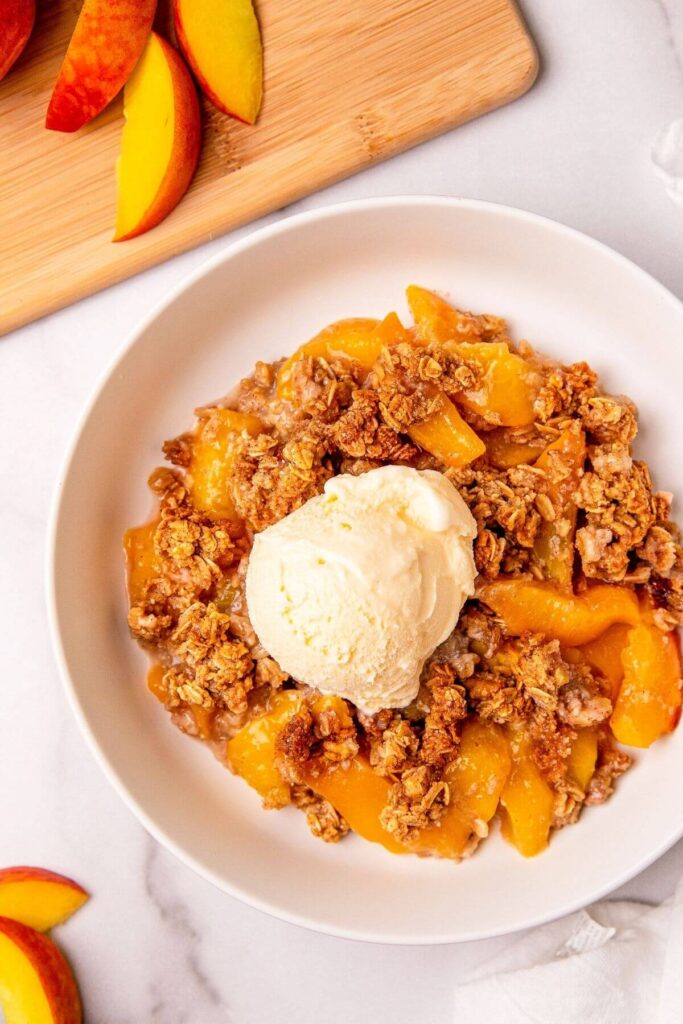 peach crumble in a bowl with ice cream