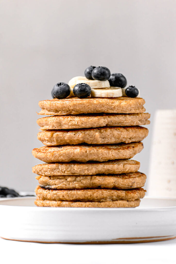 stack of protein oatmeal blender pancakes with banana and blueberries on top