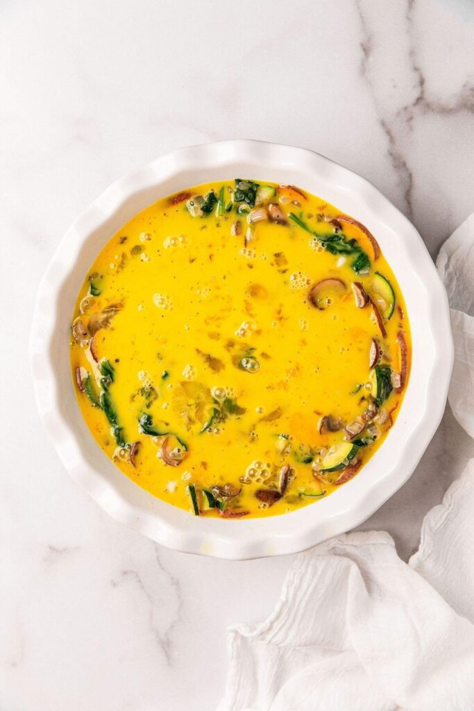 whisked eggs and veggies in pie dish to make crustless quiche