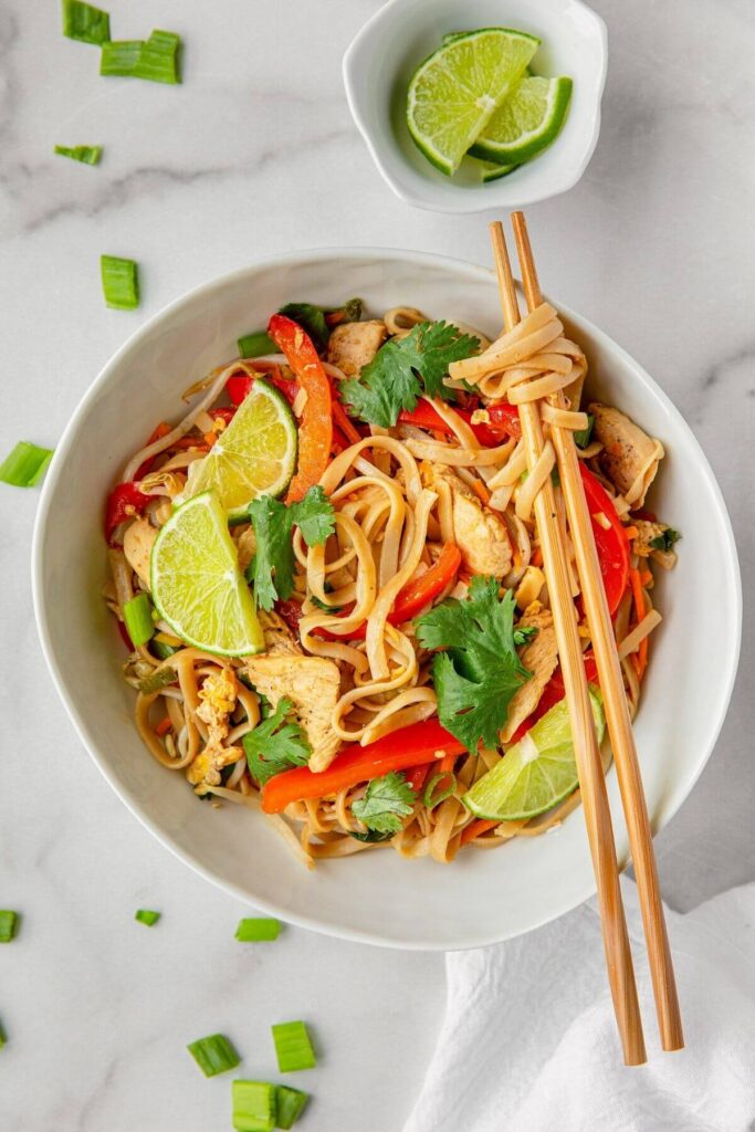 healthy chicken pad thai in a bowl with chop sticks