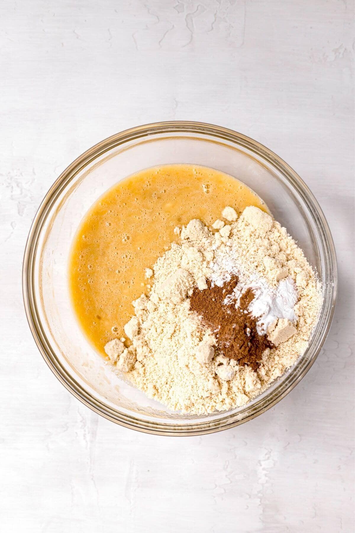 Adding almond flour, cinnamon, baking soda, and baking powder to the wet ingredients.
