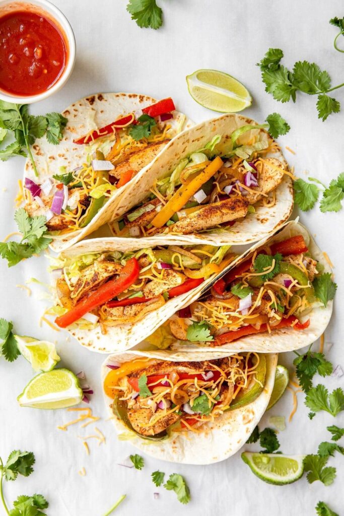healthy chicken fajita tacos with cheese and cilantro on top