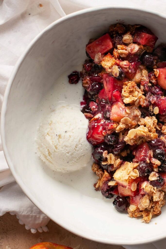 blueberry apple crumble in a bowl with vanilla ice cream