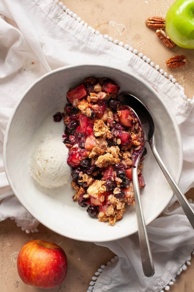 healthy blueberry apple crisp in a bowl with vanilla ice cream