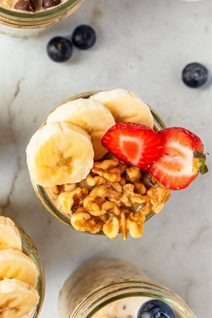 cinnamon overnight oats with walnuts, banana, and strawberries on top