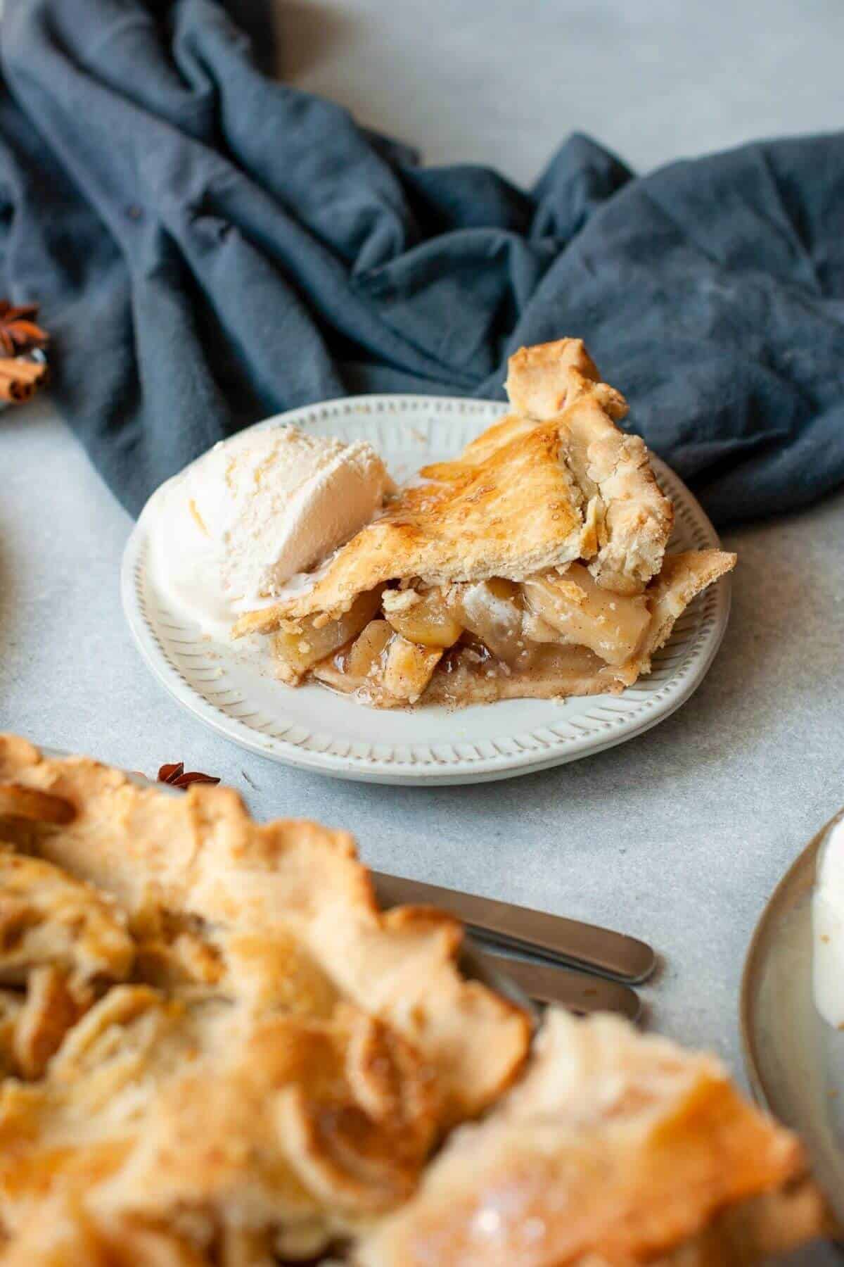 Flaky gluten-free apple pie slice with warm cinnamon apple filling and vanilla ice cream.