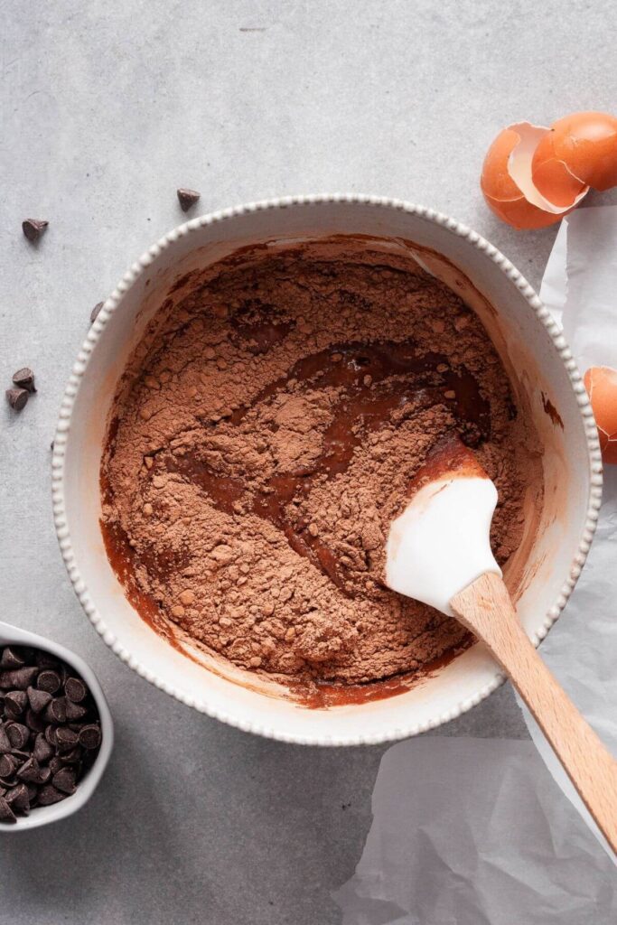 folding oat flour and cocoa powder into brownie batter