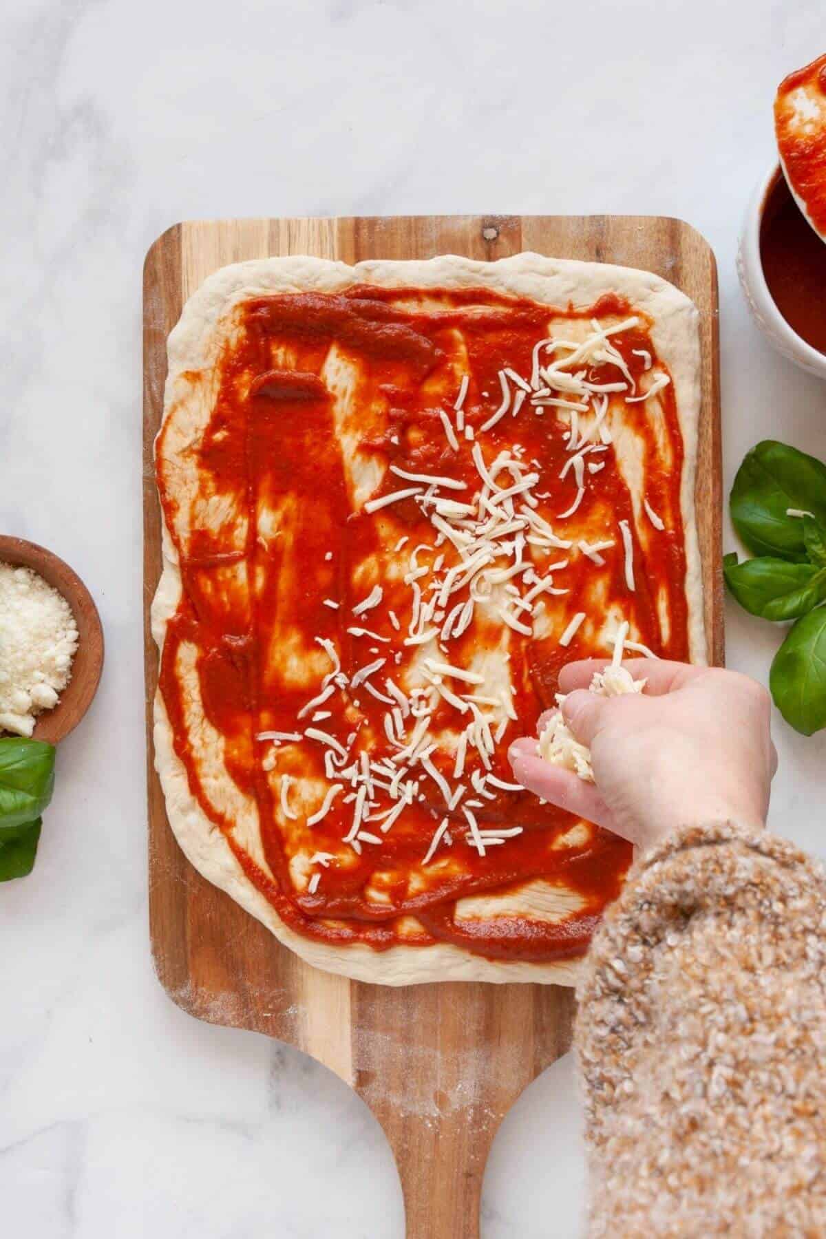 Adding mozzarella cheese on pizza dough with marinara for homemade air fryer pizza rolls.