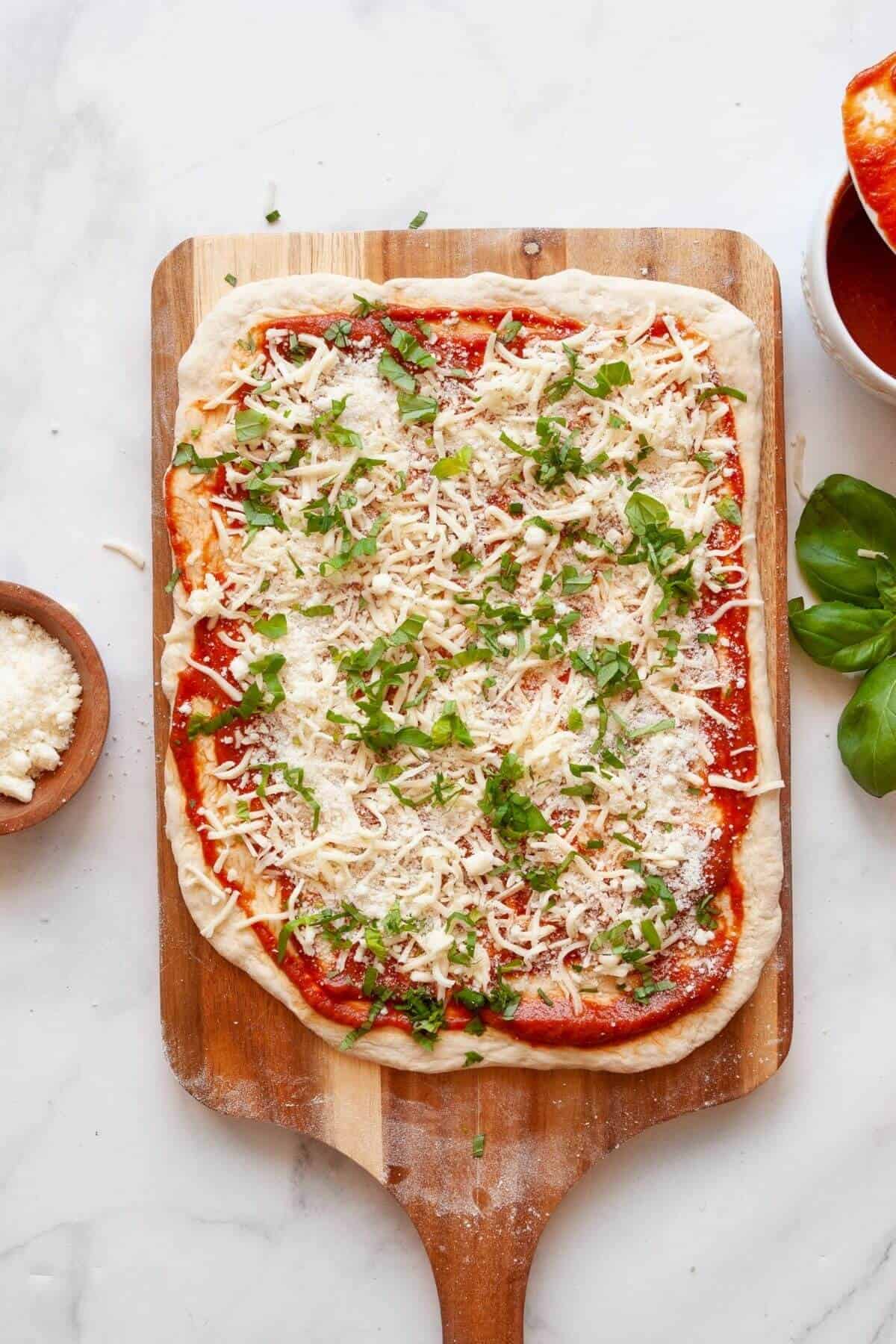 Adding fresh basil on top of mozzarella and marinara before rolling homemade air fryer pizza rolls.