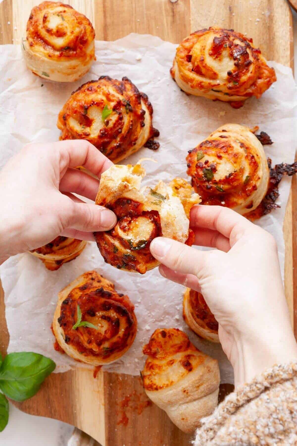 Tearing apart a cheesy homemade air fryer pizza roll to show gooey melted mozzarella and marinara filling inside.