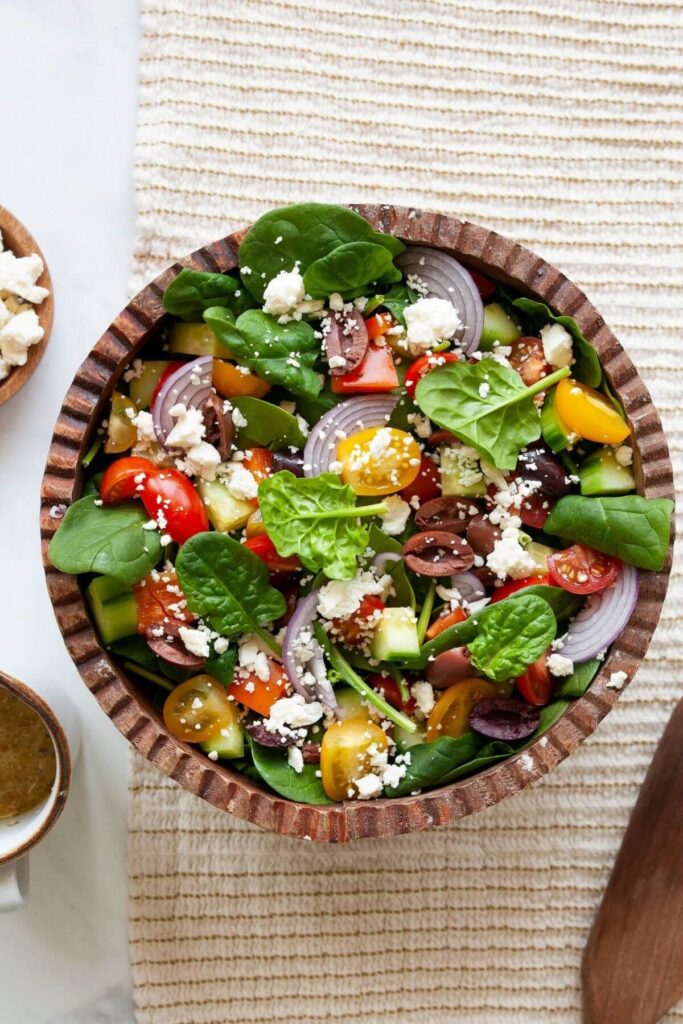 Greek salad with spinach and feta in a serving bowl