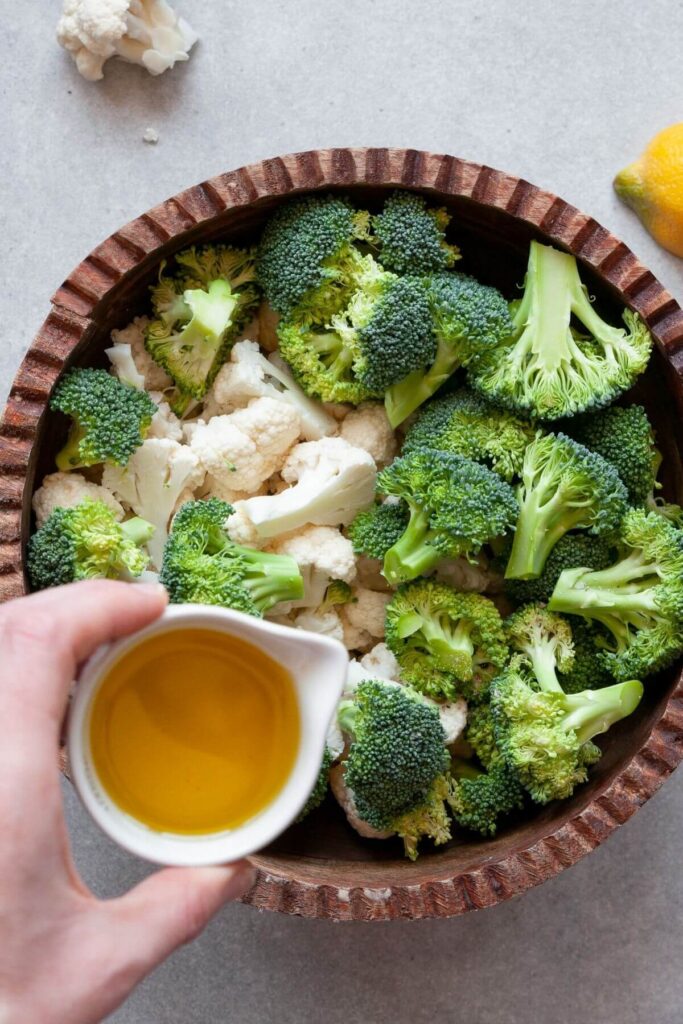 pouring olive oil on broccoli and cauliflower florets
