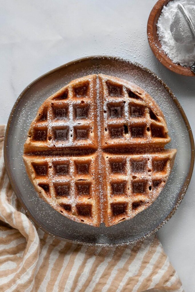 no flour banana oat waffle on a plate with powdered sugar on top