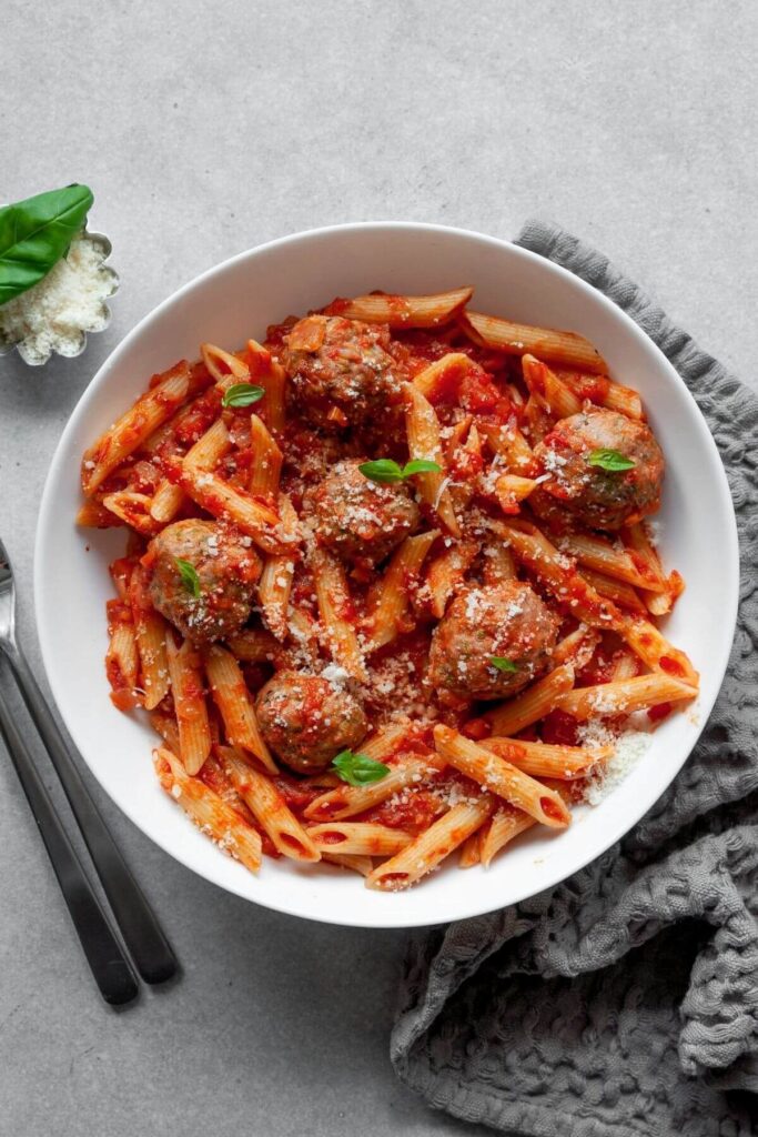 baked keto zucchini turkey meatballs with red sauce and pasta in a bowl