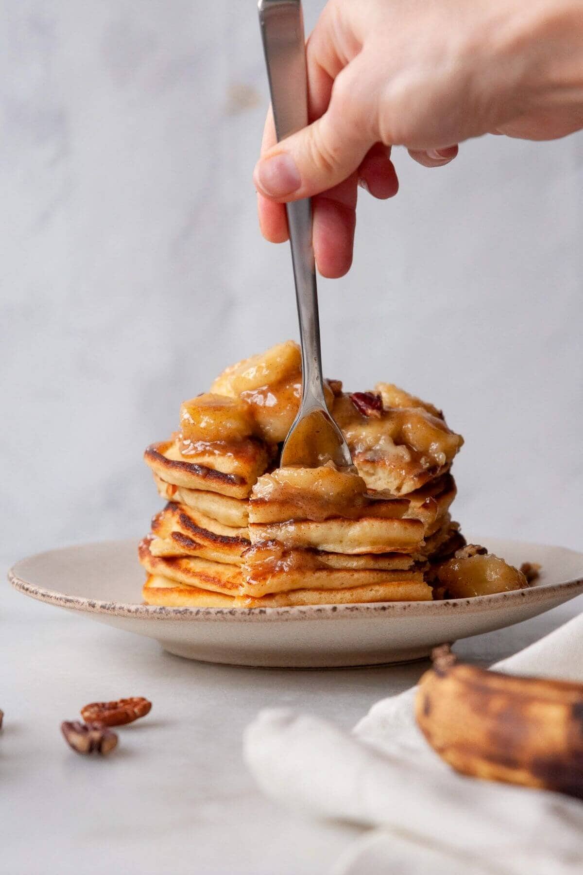 Forkful of banana foster pancakes with caramelized banana topping.