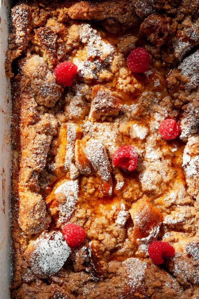close up of brioche french toast casserole with cinnamon streusel and raspberries