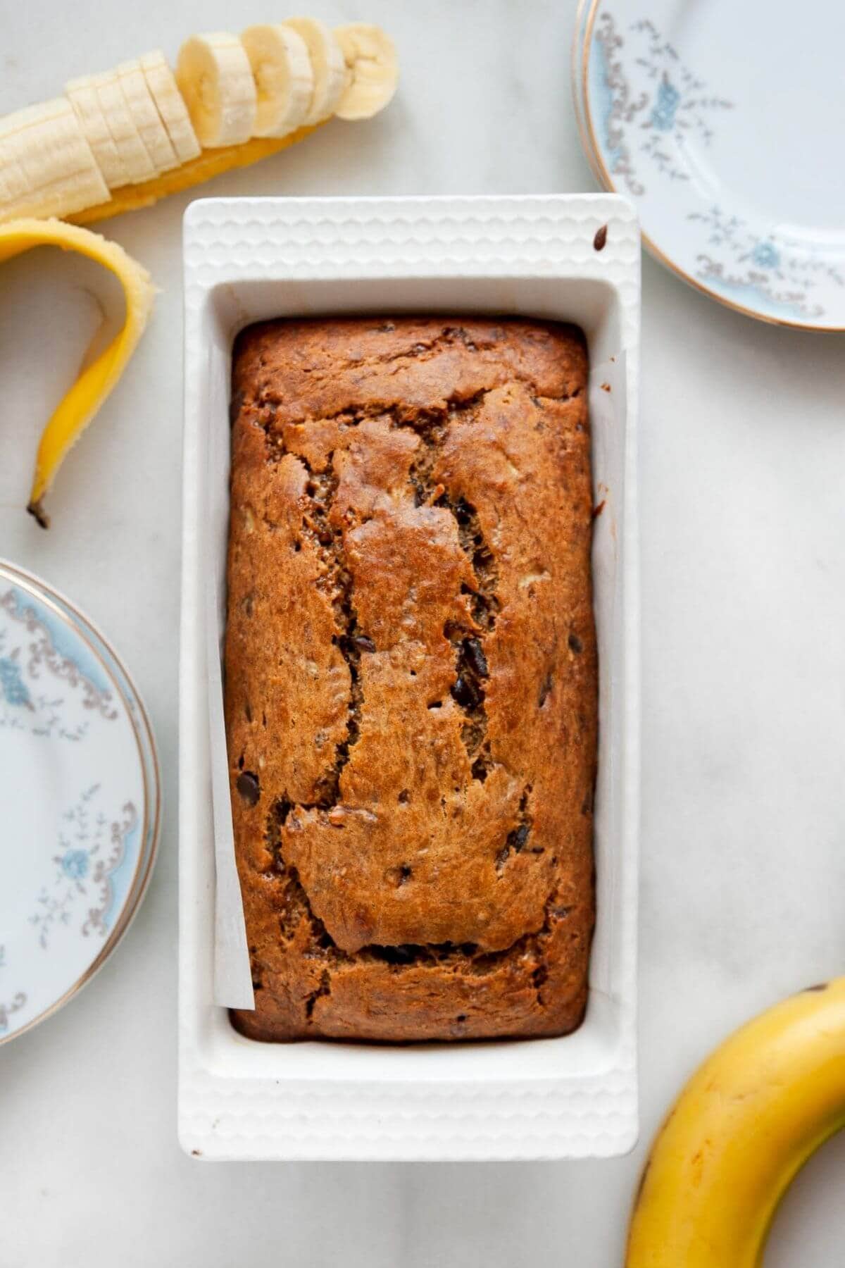 Freshly baked dairy-free banana bread loaf cooling in a parchment-lined loaf pan.