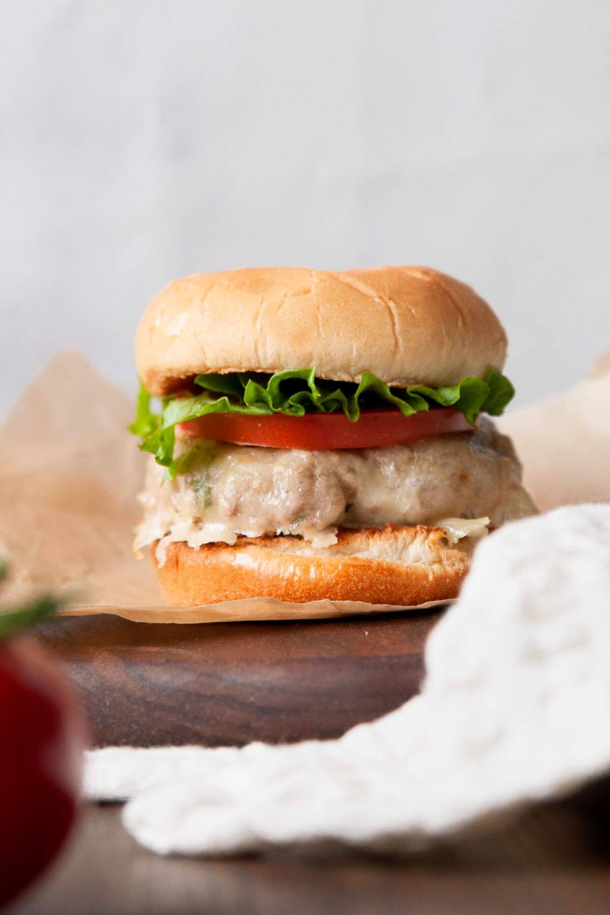 Juicy grilled turkey burger made without eggs or breadcrumbs on a bun with melted cheese, lettuce and tomato.