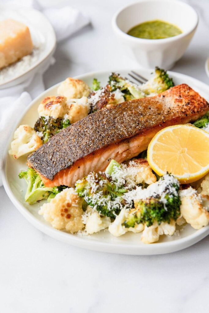 Crispy salmon on a plate with with parmesan roasted cauliflower and broccoli