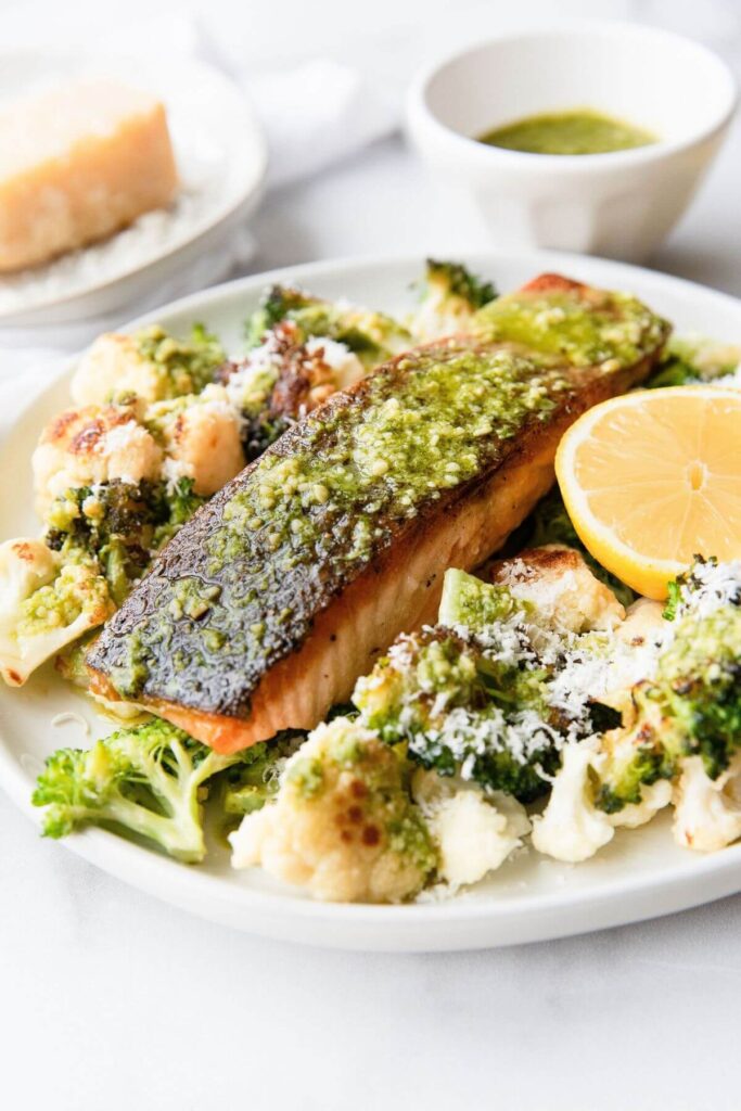 Crispy Salmon topped with homemade pesto and served with parmesan roasted cauliflower and broccoli