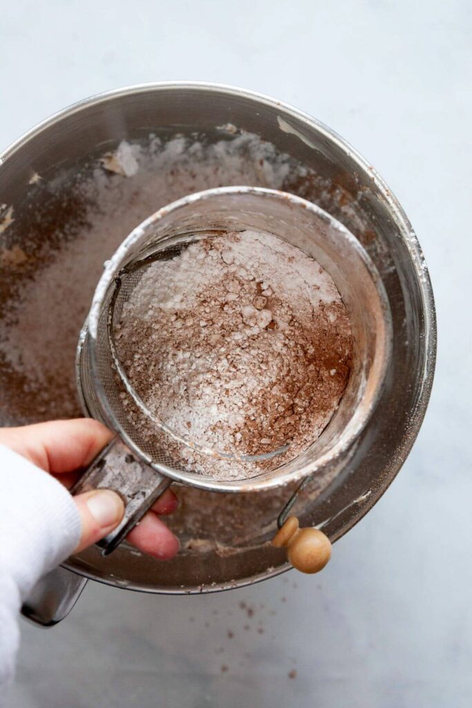 sifting powdered sugar and cocoa powder into creamed vegan butter