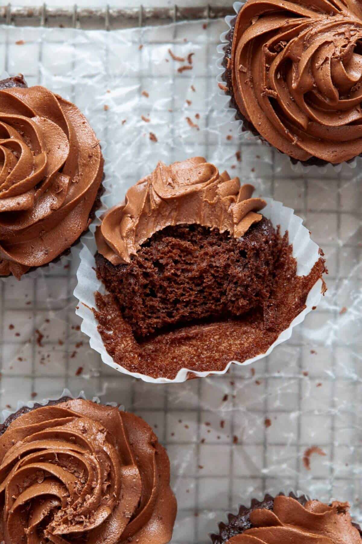 Gluten-free chocolate cupcake with a bite taken out showing the moist, fudgy interior and dairy-free chocolate frosting.