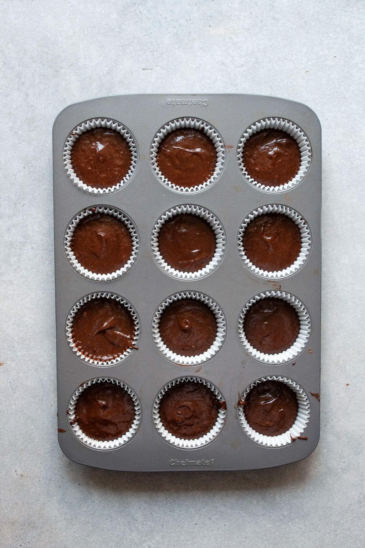 Gluten-free chocolate cupcake batter divided into paper-lined cupcake tin.