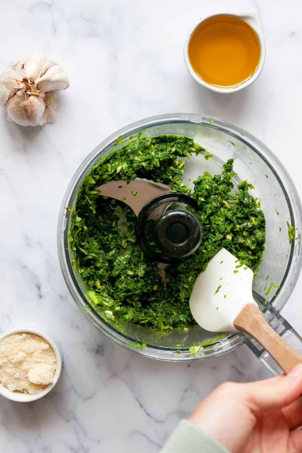 Garlic, lemon juice, salt, and pepper added to pulsed greens in food processor.