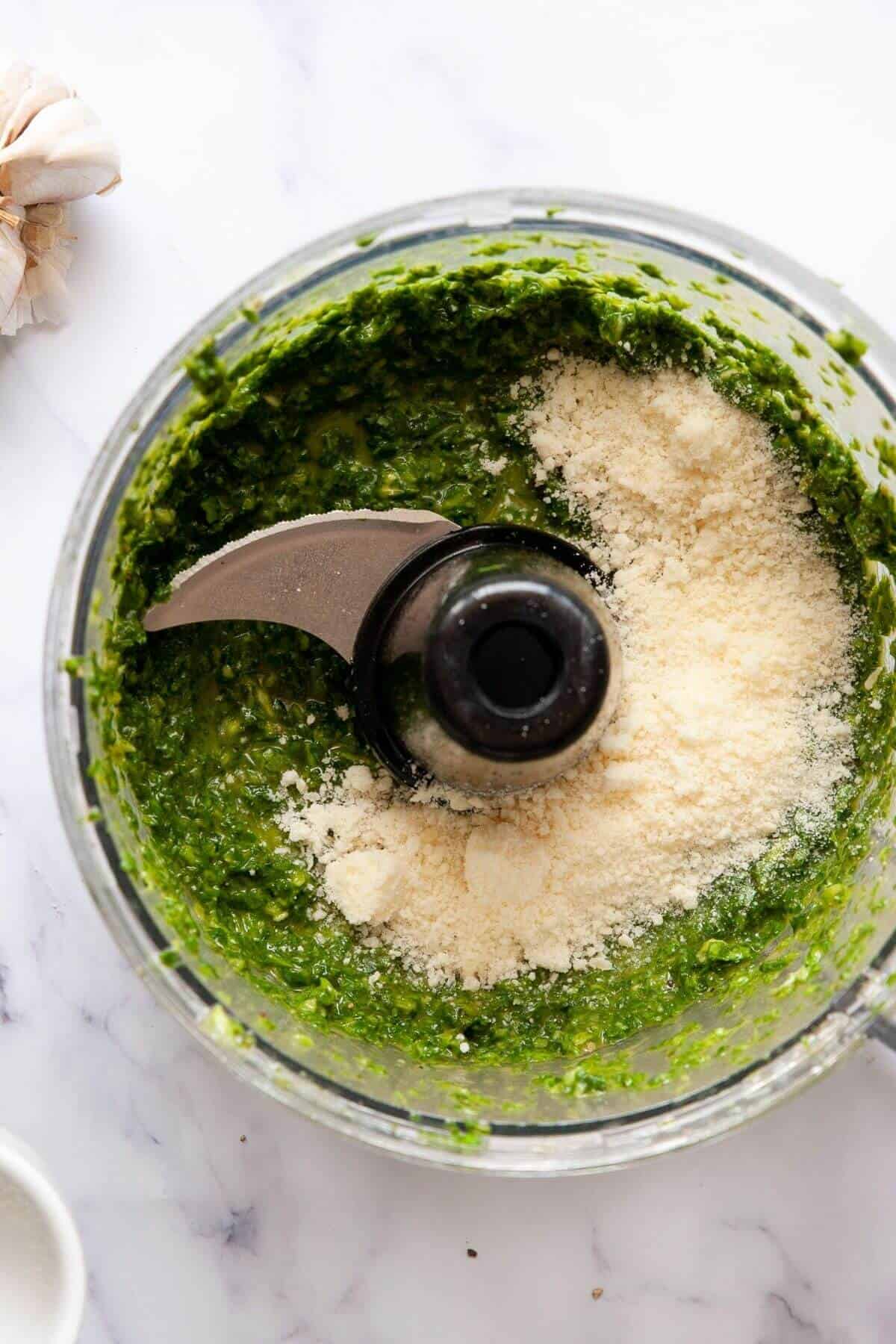 Olive oil being streamed into food processor to emulsify the nut-free pesto.