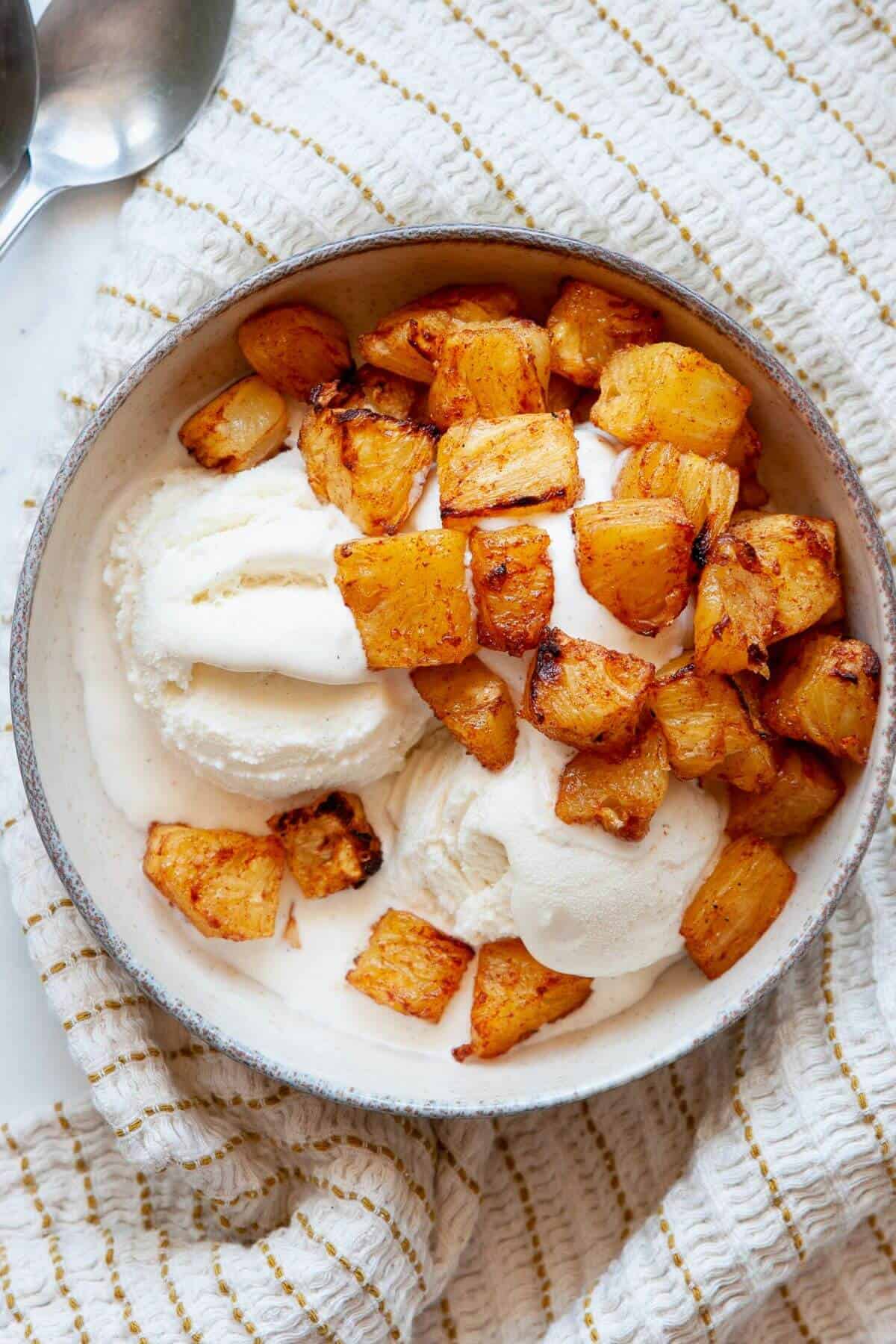 Sweet maple glazed air fryer pineapple in a bowl with vanilla ice cream.