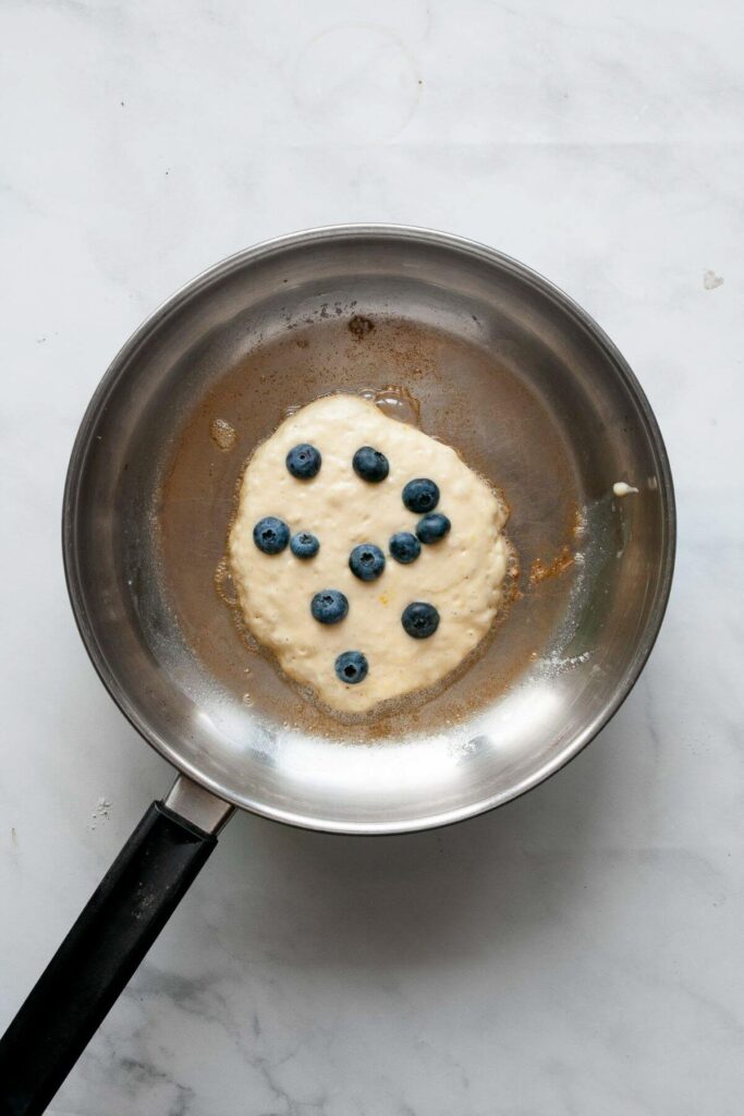 cooking a blueberry lemon pancake in a pan