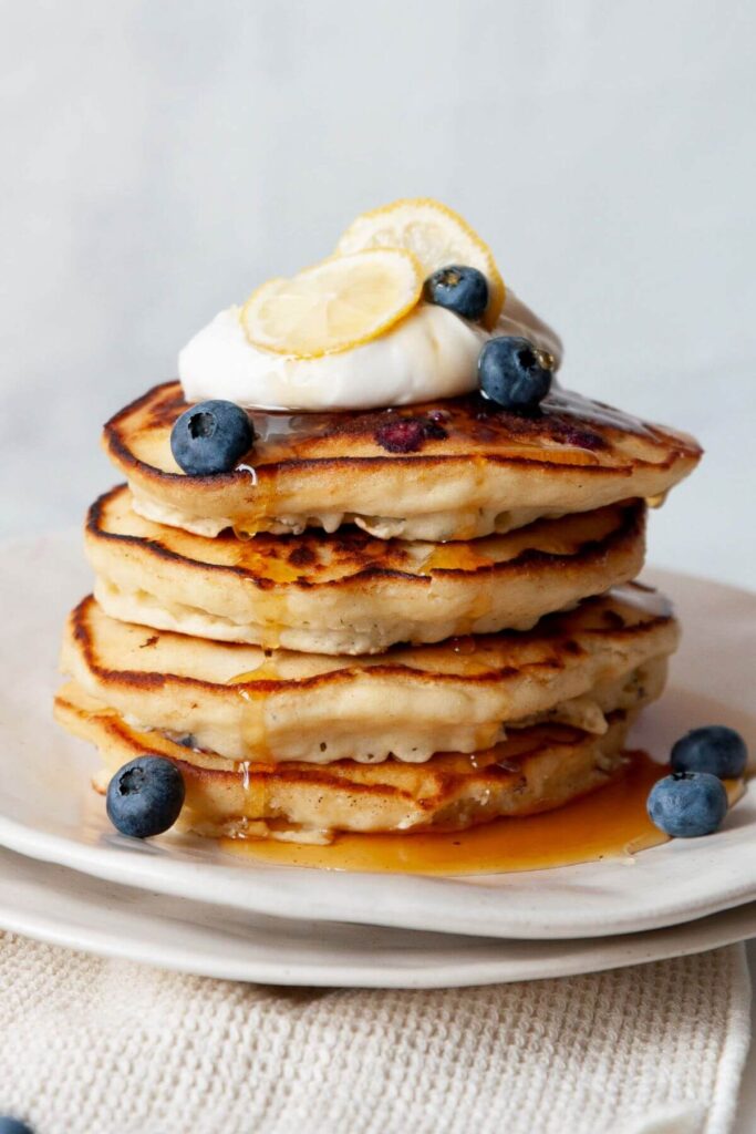 stack of fluffy blueberry lemon pancakes with crisp buttery edges and maple syrup on top