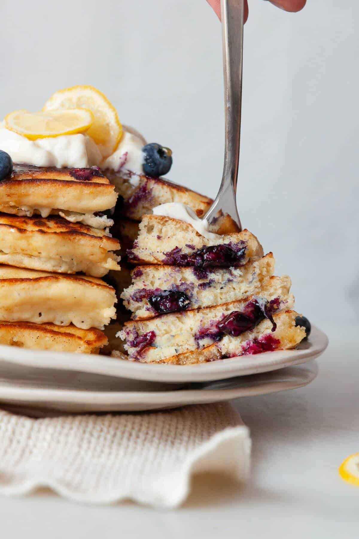 Stack of lemon blueberry pancakes with Greek yogurt and blueberries.