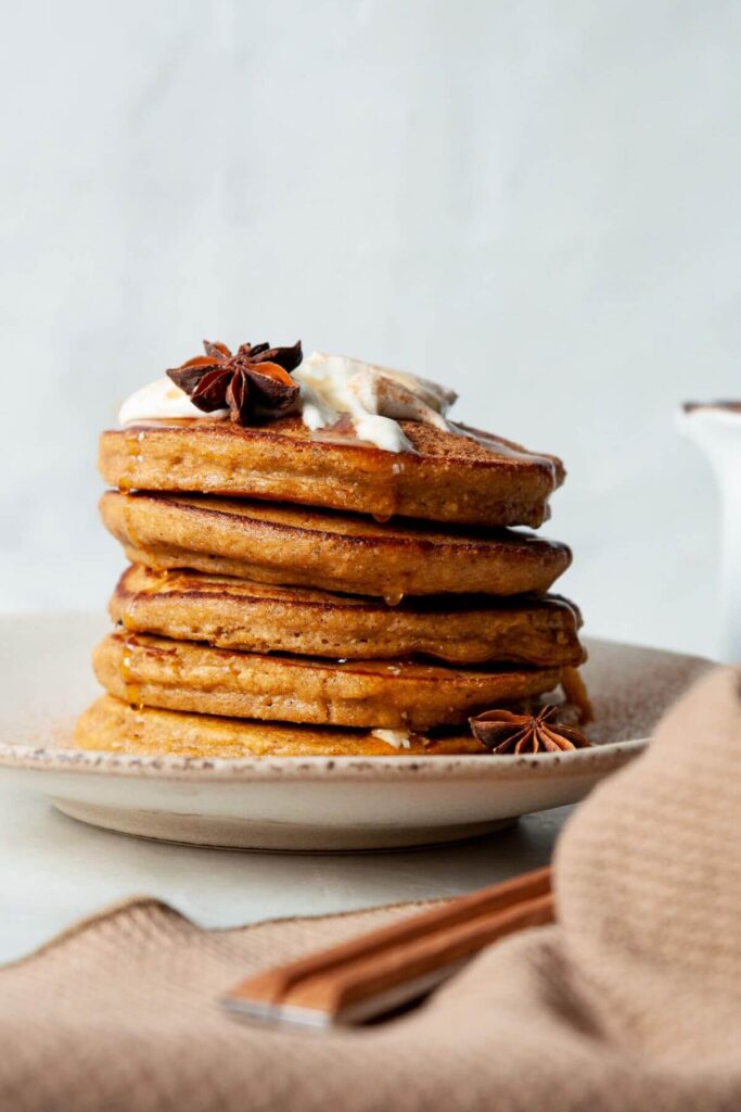 stack of oatmeal pumpkin protein pancakes with greek yogurt and maple syrup on top