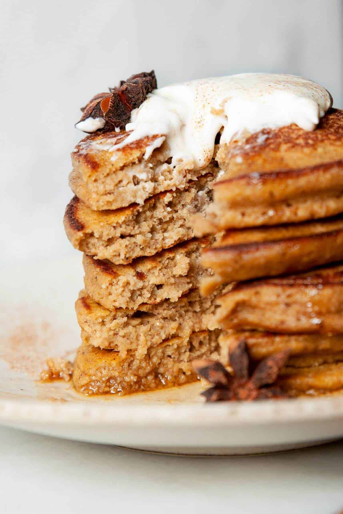 Cutting into a stack of fluffy pumpkin protein pancakes to show soft texture.