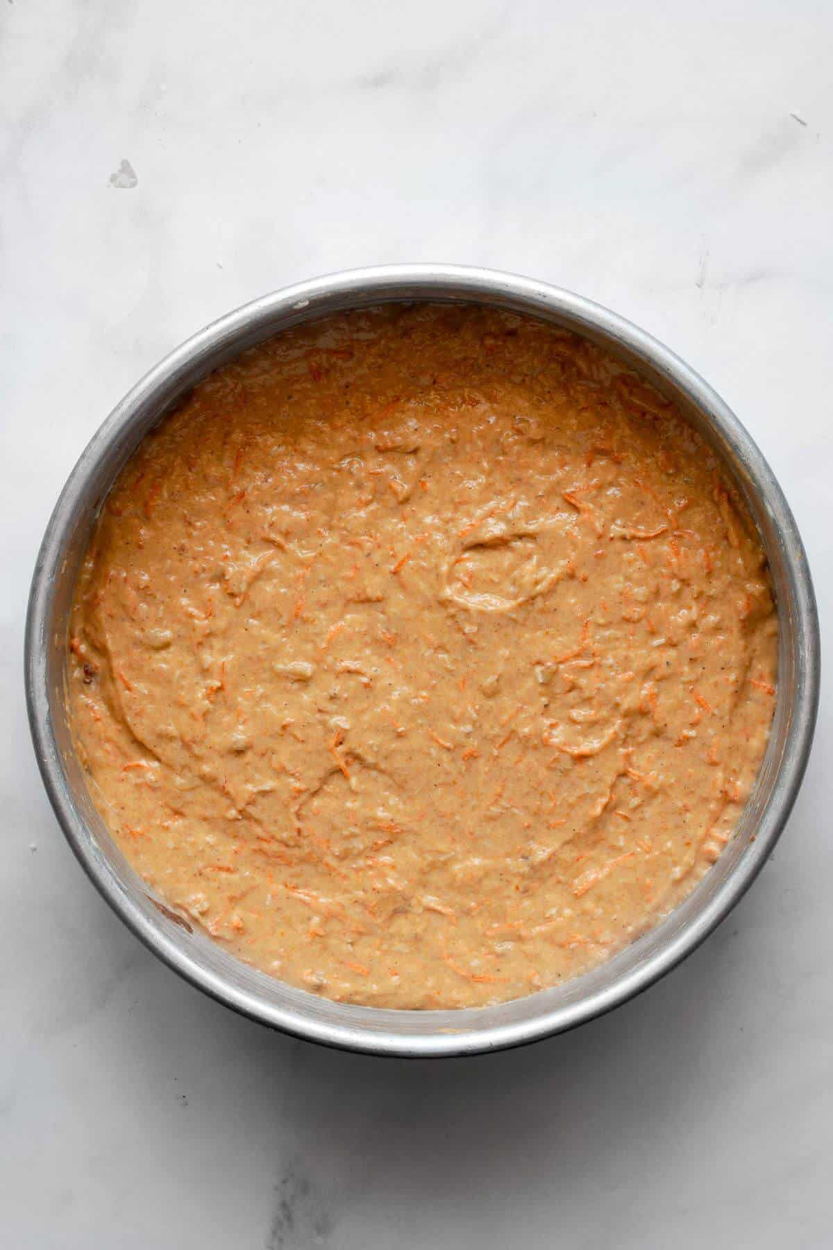 Unbaked pumpkin carrot cake batter in a greased cake pan before baking.