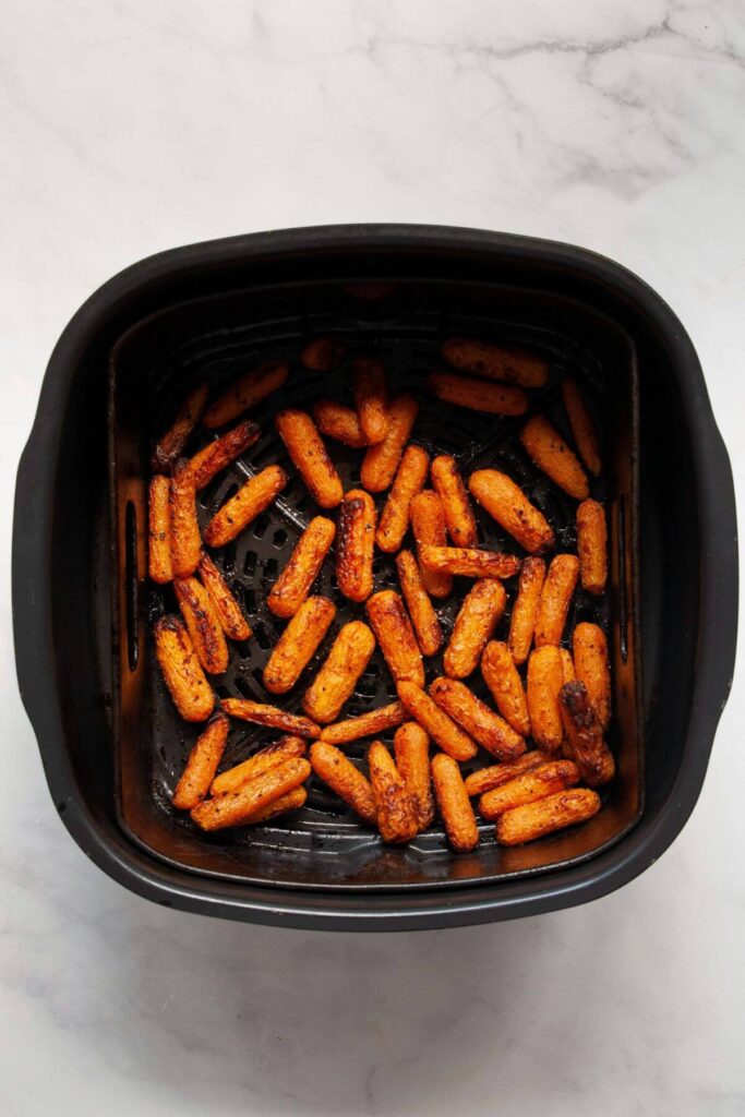 crispy baby carrots in air fryer basket after cooking