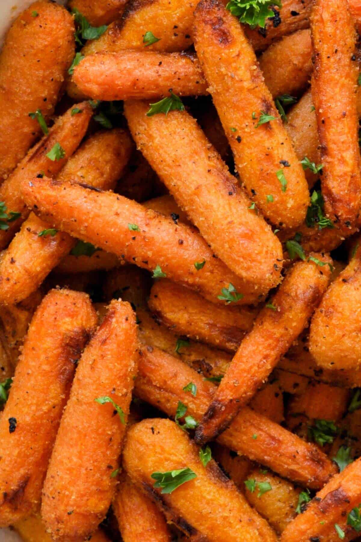 Close-up of roasted baby carrots with charred edges and chopped parsley.