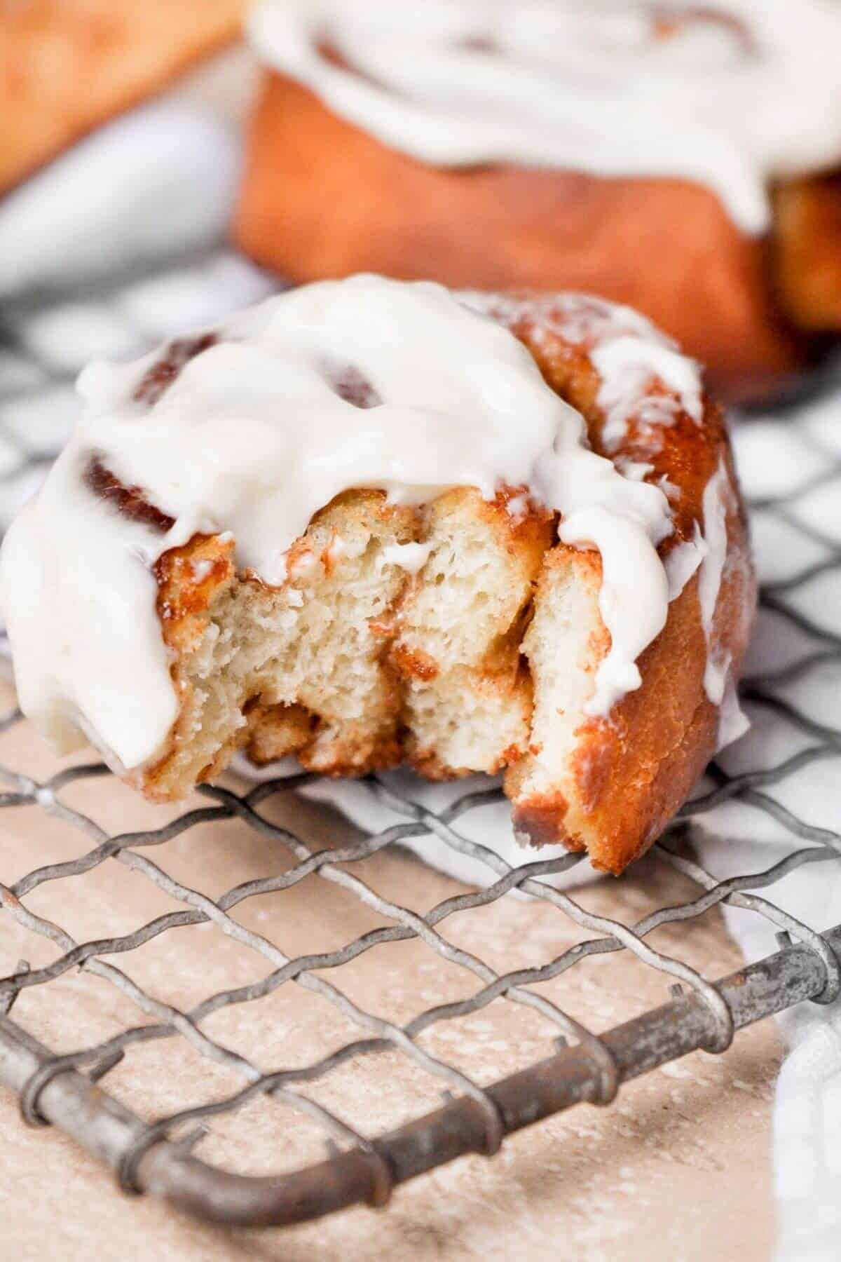 Close-up of a soft, fluffy air fryer cinnamon roll topped with cream cheese frosting.