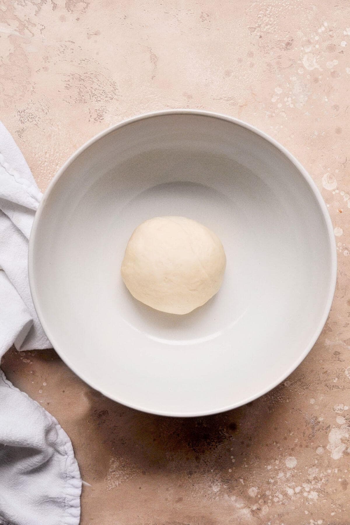 Ball of cinnamon roll dough in a bowl before proofing.