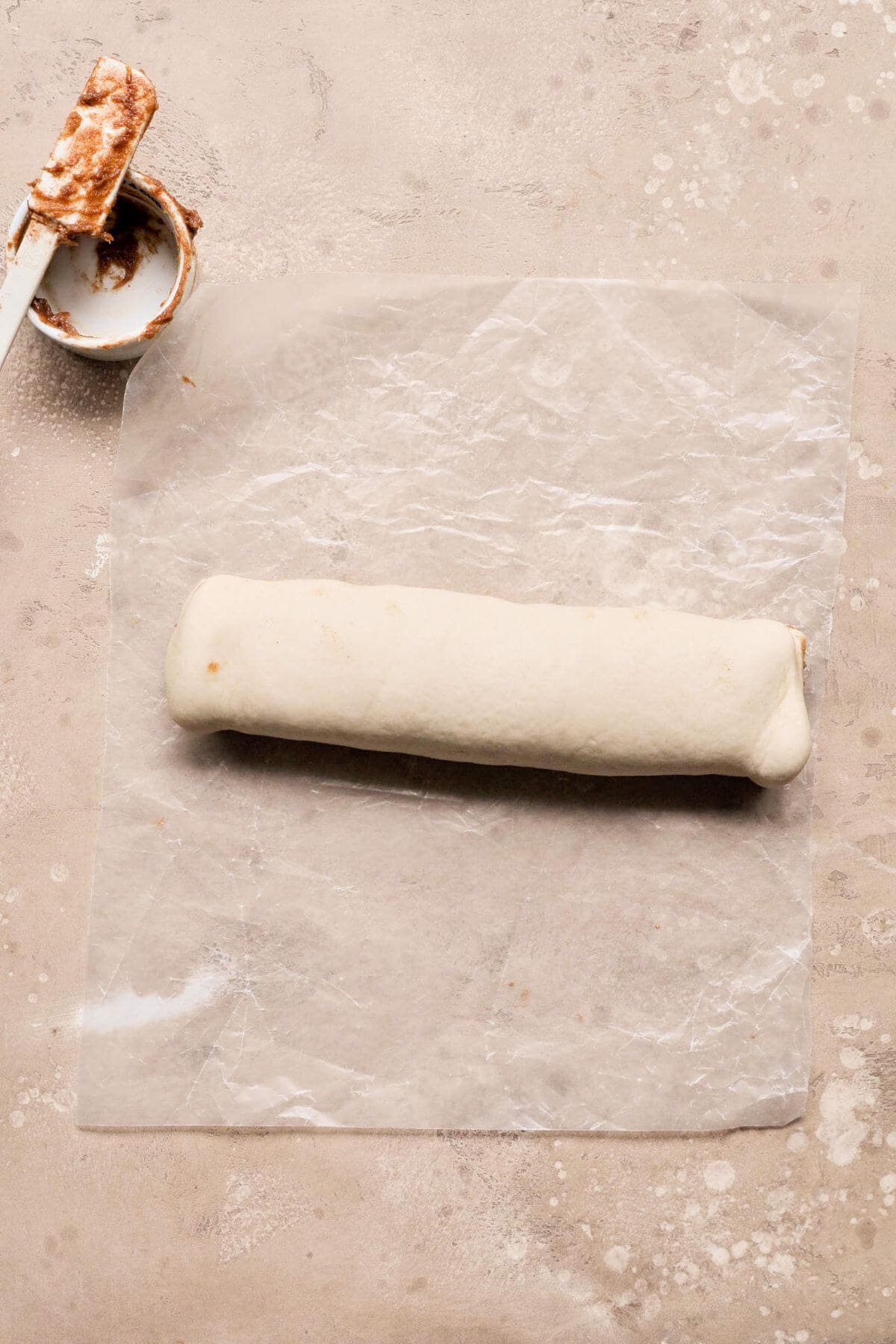 Rolled cinnamon roll dough log sealed at the edge.