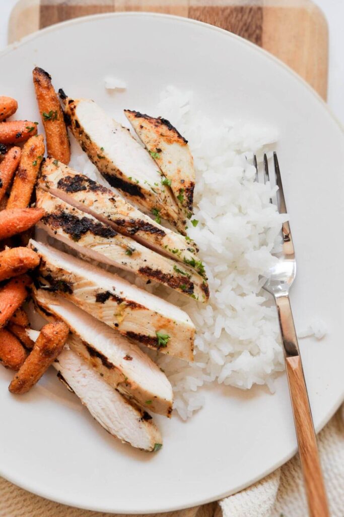 juicy yogurt chicken sliced on a serving plate with rice